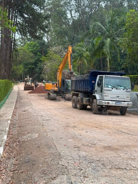 Escavadeira carregando caminhão basculante em obra dentro de condomínio